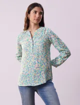 Blusa de gasa estampada con diseño abstracto en tonos celeste, amarillo y naranja. Tiene cuello a la base con escote en V y abertura con botones. Las mangas largas son de largo regulable.