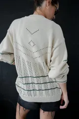 Saco de punto color crema con detalles en crochet verde, cierre frontal con botones y mangas largas.