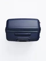 Valija rígida de viaje color azul marino con diseño de líneas horizontales. Cuenta con manija extensible, cuatro ruedas con giro de 360°, cierre con combinación numérica y organizadores internos.