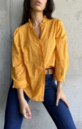 Camisa color mostaza con bordado de flores, cuello con volados, mangas largas abullonadas y cierre frontal con botones.