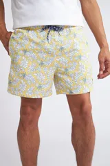 Short de baño con cintura elástica y cordón ajustable, confeccionado en tela ligera de secado rápido. Presenta un estampado botánico integral en tonos amarillos, blancos y azules, con dos bolsillos delanteros y uno posterior.