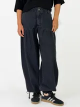 Pantalon de denim azul de corte holgado, con cintura elástica y puños ajustables con cordones en los tobillos.
