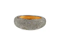 Brazalete rígido de metal dorado con diseño ancho y abovedado, completamente revestido en el exterior con incrustaciones de pedrería brillante.