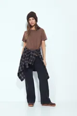 Remera de manga corta color marrón con escote a la base y calce relajado. Las mangas presentan terminación con ojales metálicos.