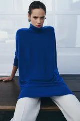 Jersey de lana en color azul vibrante, con cuello subido y diseño de manga murciélago con sisa ancha. Presenta puños ajustados y un corte holgado que se extiende hasta la cadera.