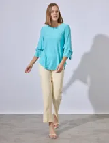 Blusa celeste de tejido piqué con mangas 3/4 y volados en los puños.