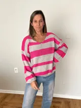 Sweater tejido a rayas fucsia y gris, con cuello en V, calce relajado y mangas amplias estilo balloon.