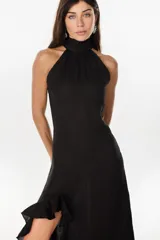 Vestido midi negro confeccionado en 100% lino italiano, con cuello alto, diseño sin mangas tipo halter y detalle de volado en el ruedo asimétrico.