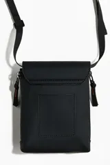 Bandolera negra de diseño rectangular, con solapa frontal y cierre de hebilla plástica. Cuenta con correa ajustable y tiras laterales decorativas.