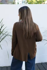 Sweater de punto color chocolate, con cuello redondo, manga larga y puños acanalados. Presenta un corte holgado con ruedo asimétrico.