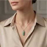 Collar de acero con baño de oro, compuesto por una cadena fina y un dije ovalado de piedra natural amazonita con una circonia azul engastada en el centro.