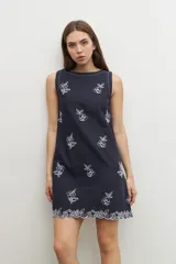 Vestido corto azul marino con bordado floral blanco, sin mangas y corte recto.