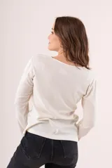 Camiseta blanca de manga larga con escote en V y detalle bordado en el centro del pecho.