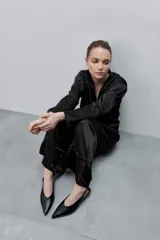 Pantalón de pierna amplia y calce holgado, color negro, confeccionado en tejido satinado. Cuenta con cintura elastizada, recortes horizontales y tiras regulables en los ruedos.