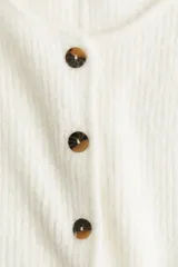 Saco de punto acanalado con cuello redondo, cierre frontal con botones y diseño de peplum con vuelo en la parte inferior.
