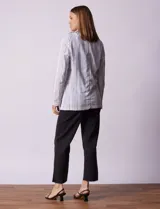 Blazer blanco con rayas verticales negras, cuello con solapa, abertura central con botón y bolsillos delanteros.