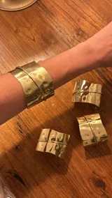 Brazalete rígido dorado con textura martillada y diseño envolvente.