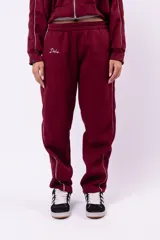 Conjunto deportivo compuesto por una campera con cierre y un pantalón de jogging, ambos de color negro con detalles de líneas blancas laterales. El pantalón presenta un corte holgado y cómodo.