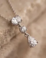 Collar de acero con colgante de tres circonias: una ovalada en la parte superior, una pequeña redonda en el centro y una circonia en forma de lágrima en la base.
