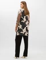 Conjunto de tres piezas compuesto por una musculosa negra con escote en V, un pantalón palazzo de tejido de punto liso con cintura elástica y una túnica larga de tul negro con mangas 3/4. La túnica presenta un bordado floral detallado con aplicaciones de lentejuelas.