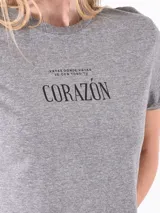 Remera gris de corte crop con cuello redondo y mangas cortas. Presenta un estampado frontal con la frase 'Vayas donde vayas ve con todo tu corazón'.