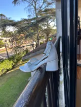Sandalias de cuero blanco con taco bajo, tira delantera simple, talón cerrado y pulsera ajustable al tobillo con hebilla dorada.
