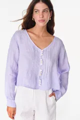 Camisa blanca de lino italiano, de manga larga, escote en V y cierre frontal con múltiples botones y detalles de alforzas.