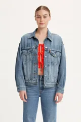Campera de jean estilo trucker con corte relajado, diseño clásico de los años 90, cuello camisero, cierre frontal con botones metálicos, dos bolsillos con solapa en el pecho y puños abotonados.