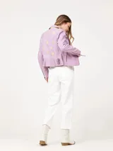 Chaqueta de cuero color lila, estilo biker, con cierre asimétrico y detalles de cremalleras plateadas.