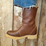 Botas de cuero color tostado con caña baja y vuelta de corderito sintético, suela track de goma y cordones frontales.