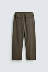 Pantalón regular fit color marrón oscuro, confeccionado en tejido con viscosa. Cuenta con cintura elástica, bolsillos delanteros y detalle de bolsillos traseros de vivo. El cierre frontal es con cremallera y botón.