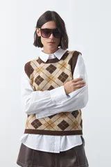 Chaleco tejido sin mangas con diseño de rombos tipo argyle en tonos marrón y beige, con cuello redondo y terminaciones acanaladas.