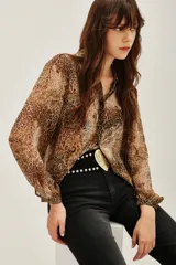 Camisa de manga larga con estampado de leopardo, confeccionada en tejido ligero y semitransparente. Presenta cuello clásico, cierre frontal con botones y puños abotonados.
