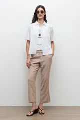 Camisa blanca de manga corta con sutiles detalles bordados tonales, cierre frontal de botones y cuello camisero.