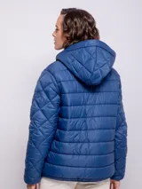 Campera capitoneada color ladrillo con capucha, cierre frontal con botones a presión y cremallera, bolsillos laterales y puños elastizados.