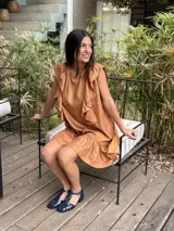 Vestido corto de lino metalizado color dorado, de corte holgado, con volados en los hombros y en el ruedo.