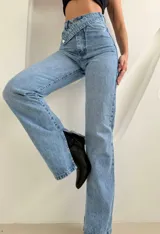 Jean de tiro alto en color azul claro, con diseño de cintura cruzada asimétrica y tajos laterales en el ruedo.