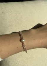 Pulsera con cuentas de cristal facetado color rosa, perla barroca de río y detalles en acero dorado con baño de oro.