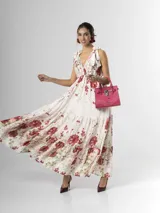 Vestido largo confeccionado en mezcla de tencel y lino, con fondo off white y estampado floral en tonos rosados, rojos y verdes. Cuenta con escote en V pronunciado, breteles anchos ajustables con lazos en los hombros, corte bajo el busto y falda amplia con volados escalonados.