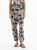 Pantalón tipo babucha de tiro alto y silueta holgada, confeccionado en mezcla de viscosa y cupro con un estampado geométrico y floral. Posee cintura con frunces y puños elastizados en los tobillos.