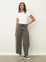 Jean de corte wide leg en color gris con efecto lavado. Presenta tiro medio, cierre frontal con botón y bolsillos laterales y traseros.