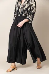 Pantalón ancho de seda color negro, con cintura elastizada y caída fluida.