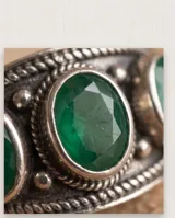 Anillo de plata envejecida con diseño ancho y tres piedras naturales verdes ovaladas dispuestas en línea.