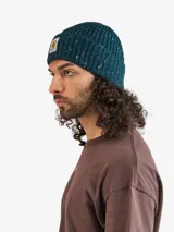 Gorro tipo beanie de tejido de punto con textura acanalada y efecto moteado multicolor. Presenta una etiqueta cuadrada con el logo de la marca en el frente.