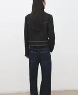 Chaqueta corta confeccionada en tejido texturizado con mezcla de algodón, poliéster y lana. Presenta cuello solapa, mangas largas, bolsillos frontales con solapa y cierre mediante botones metálicos dorados. Los bordes cuentan con detalles de flecos deshilachados.