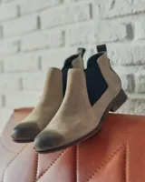 Botín Chelsea de cuero color beige con elástico lateral negro, puntera redondeada y suela plana.