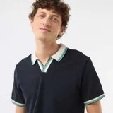 Remera de piqué de algodón color azul marino, con cuello polo en contraste color crema y detalles de rayas verdes y blancas en el cuello y los puños.