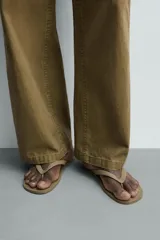 Sandalia plana de goma, color verde oscuro con tiras cruzadas en el empeine en tono beige.