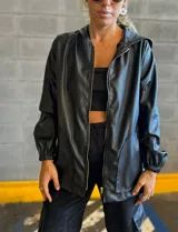 Campera negra con capucha, cierre frontal con cremallera dorada, bolsillos laterales y puños elásticos.