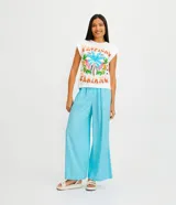 Pantalón acampanado de lino color celeste, con bolsillos, cinturón bordado y pliegues delanteros.